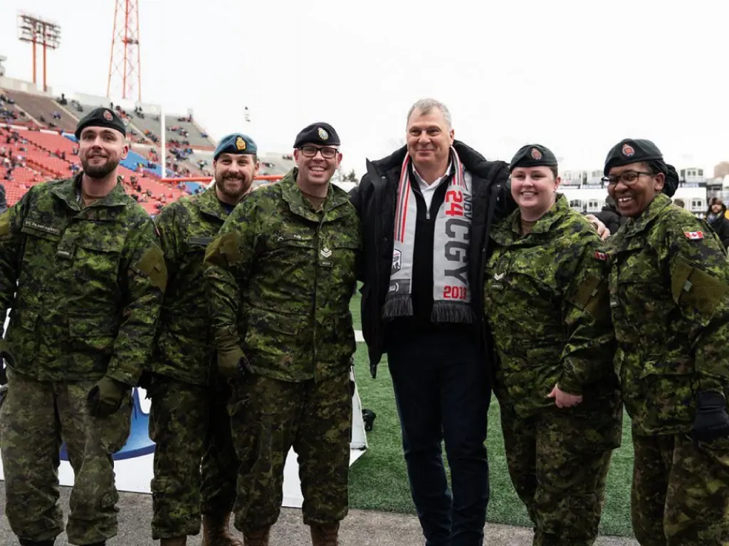 The CFL commissioner Randy Ambrosie stood in-between Royal Canadian Air Force police officers at McMahon Stadium during the 2019 Grey Cup.