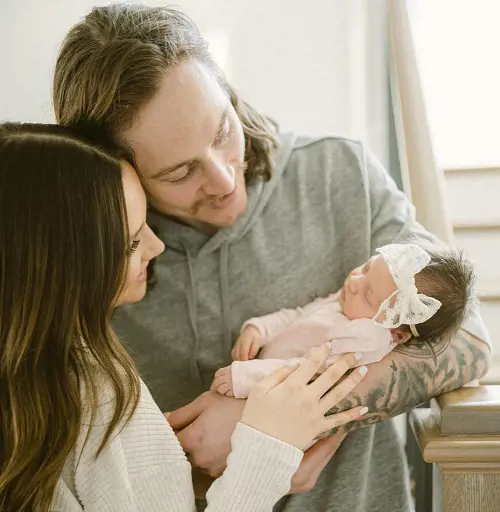 Tyler Bertuzzi cradles his baby daughter Kinsley Lea Bertuzzi as his soon-to-be wife Ashley Greasley looks on 