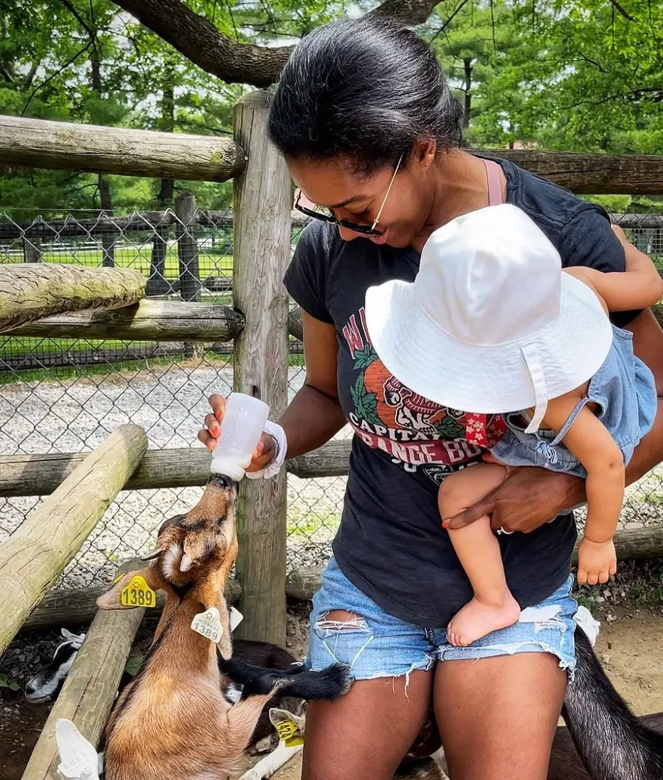 Sherree Burruss feeding goat while holding her daughter at the Grant's farm.